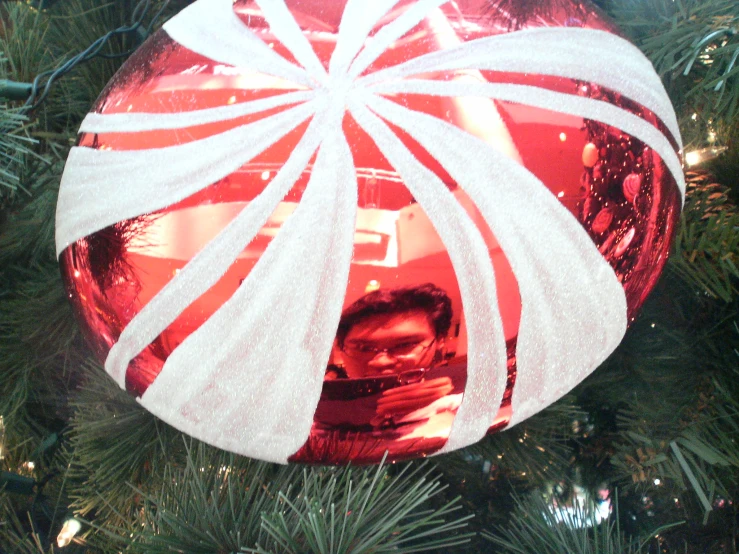 a large ornament with a man holding a camera and candy canes attached to it