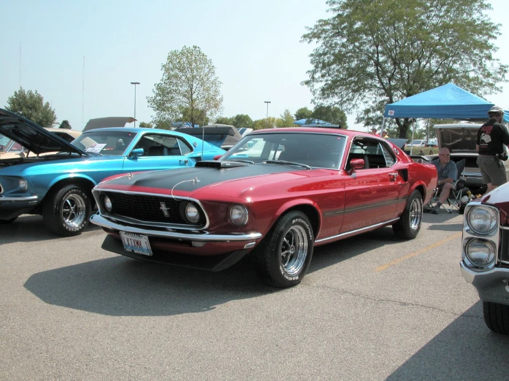 old fashioned mustang coupes parked on the pavement near blue tents