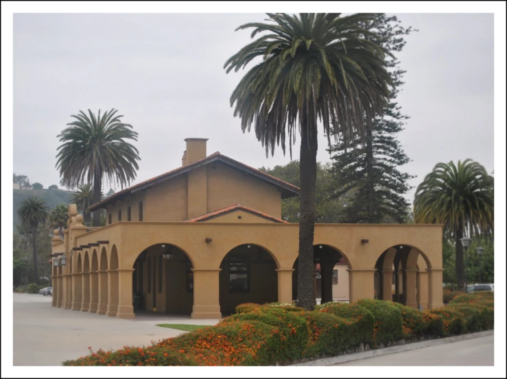 the front of an adobe styled building in palm trees and bushes