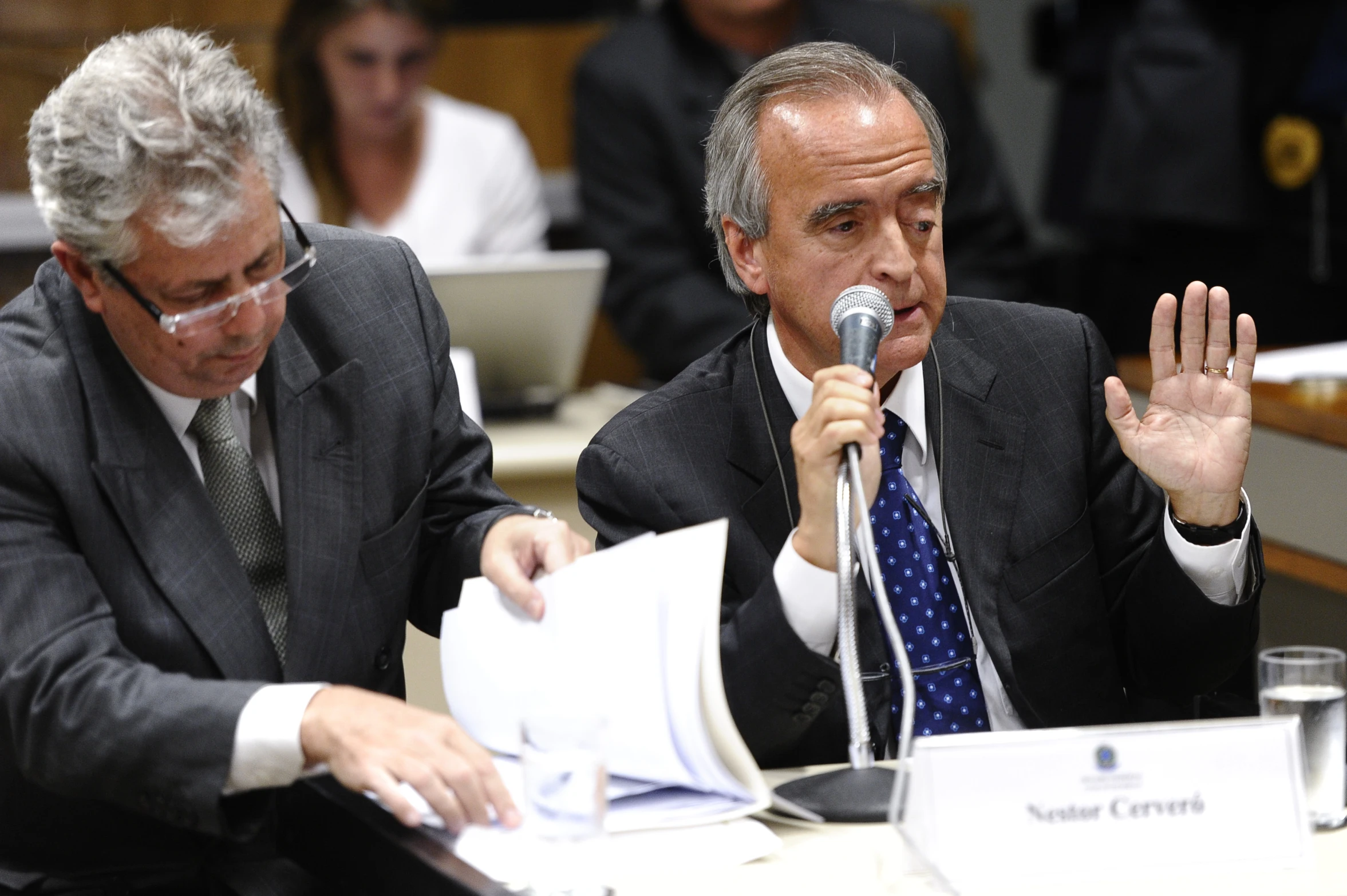 two men in suits sitting at a table