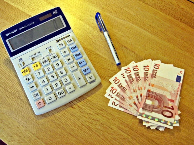 a calculator next to five currency on a table