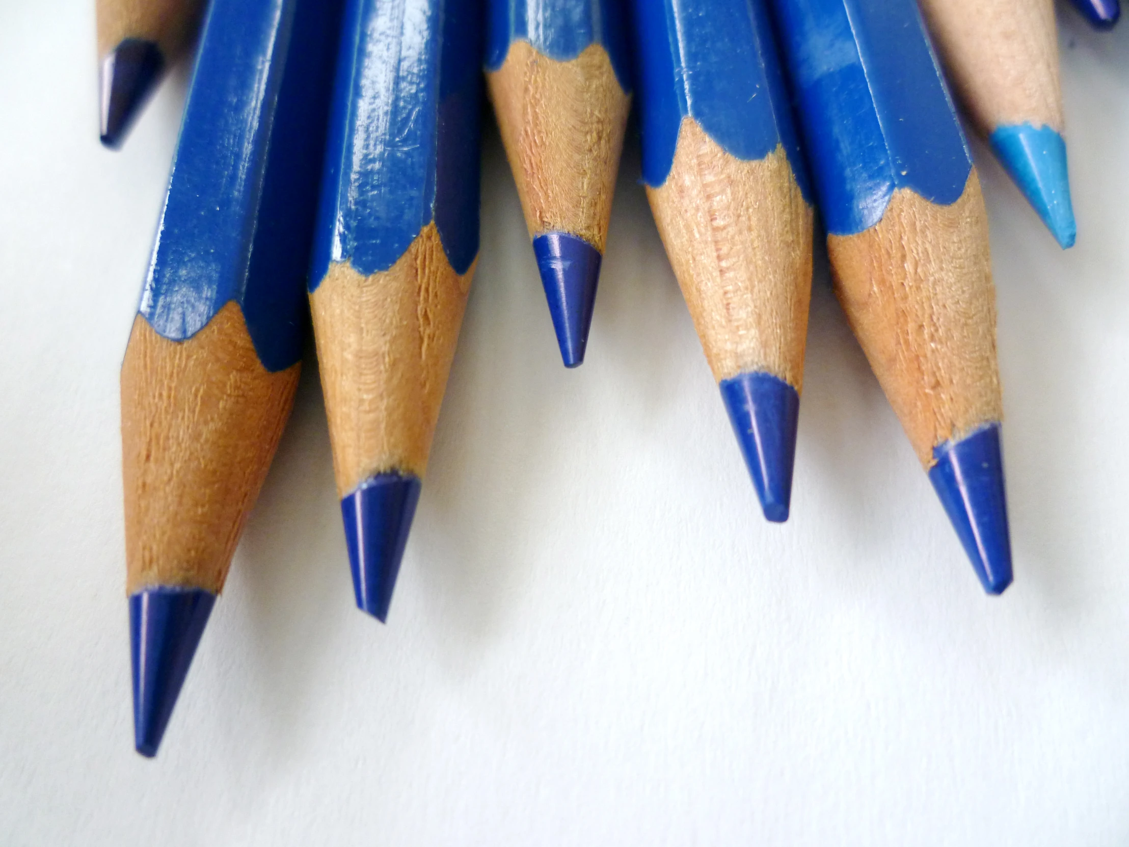 blue pencils with pointed ends on a white surface