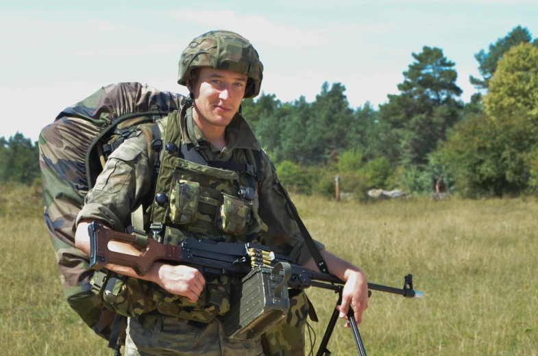 man in camouflage carrying large machine gun on shoulder