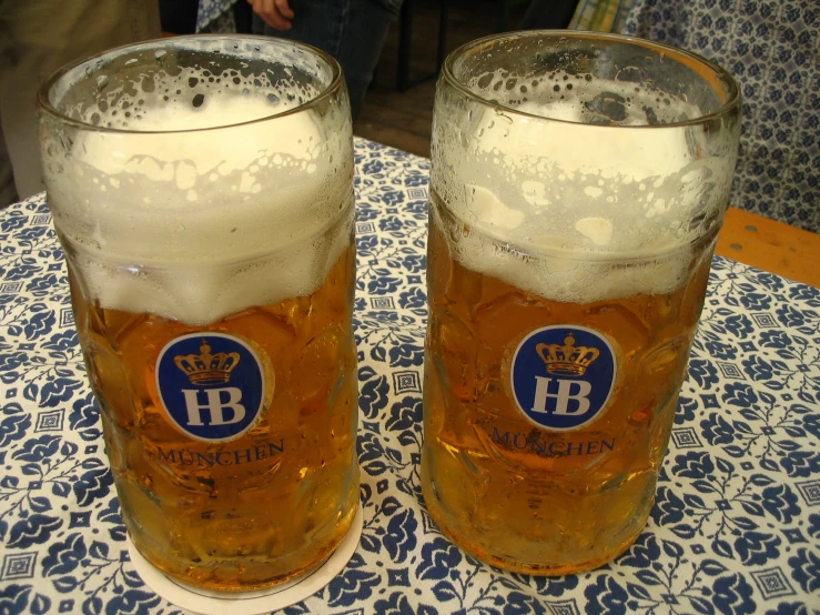 two large glasses filled with beer are shown