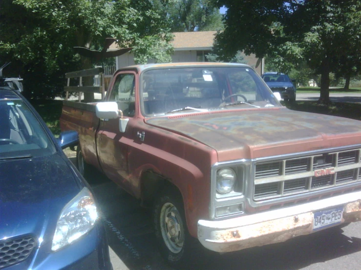 an old pick up truck is parked next to another car