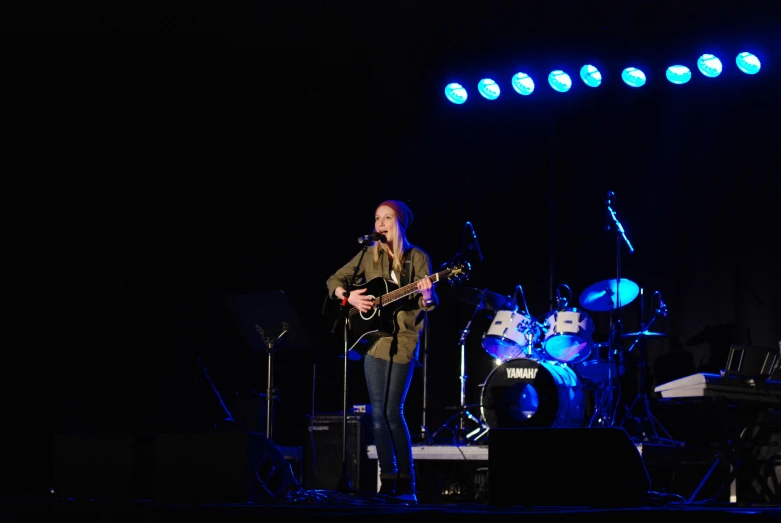 man playing guitar and singing on stage in dark