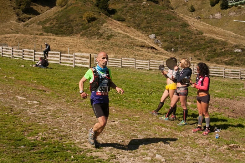 three people that are in the grass running