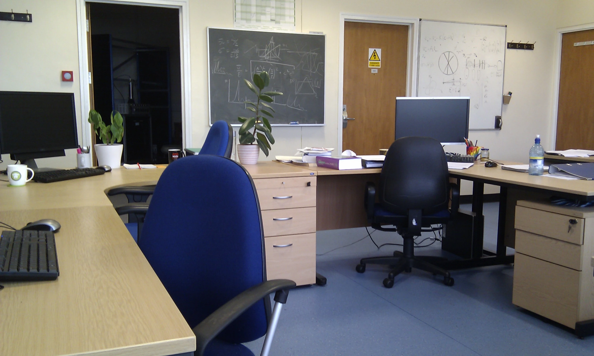 an office with two desks and a blackboard