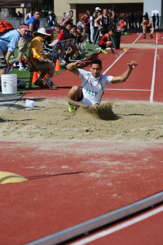 a man diving into a pile of sand with people behind him