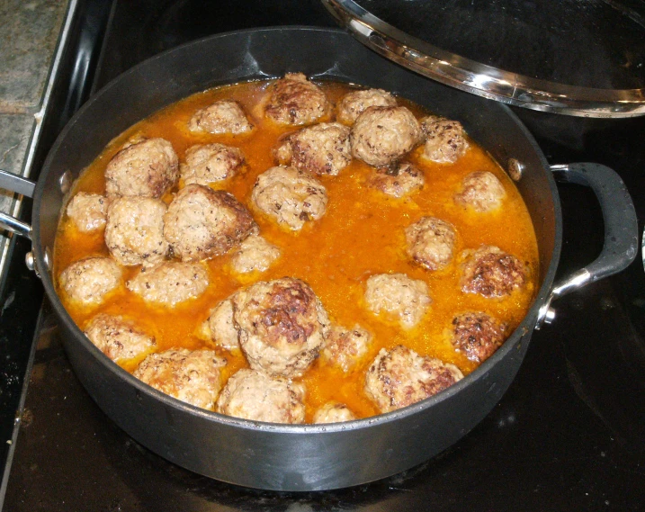 a set with meatballs in sauce is cooking on a stove