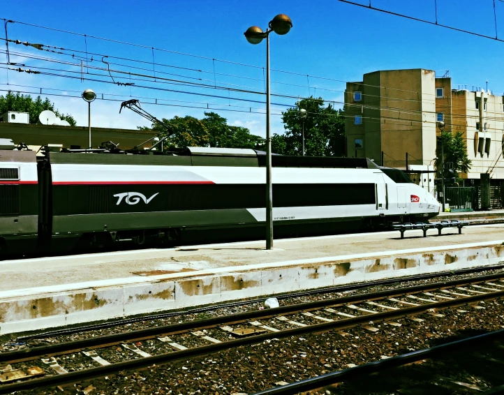 a white and black train passing by buildings