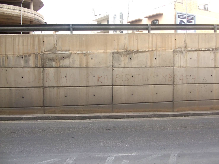 a bus driving down a city street next to a cement wall