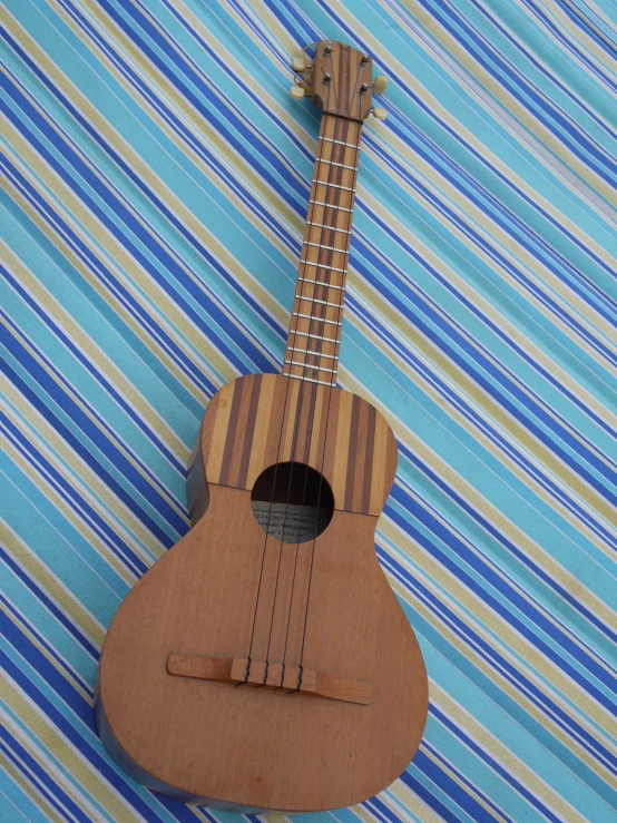 an ukulele is lying on a blue and green  fabric
