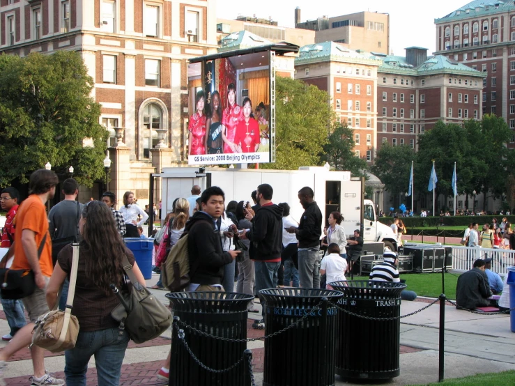 crowd of people walking on brick sidewalk next to building