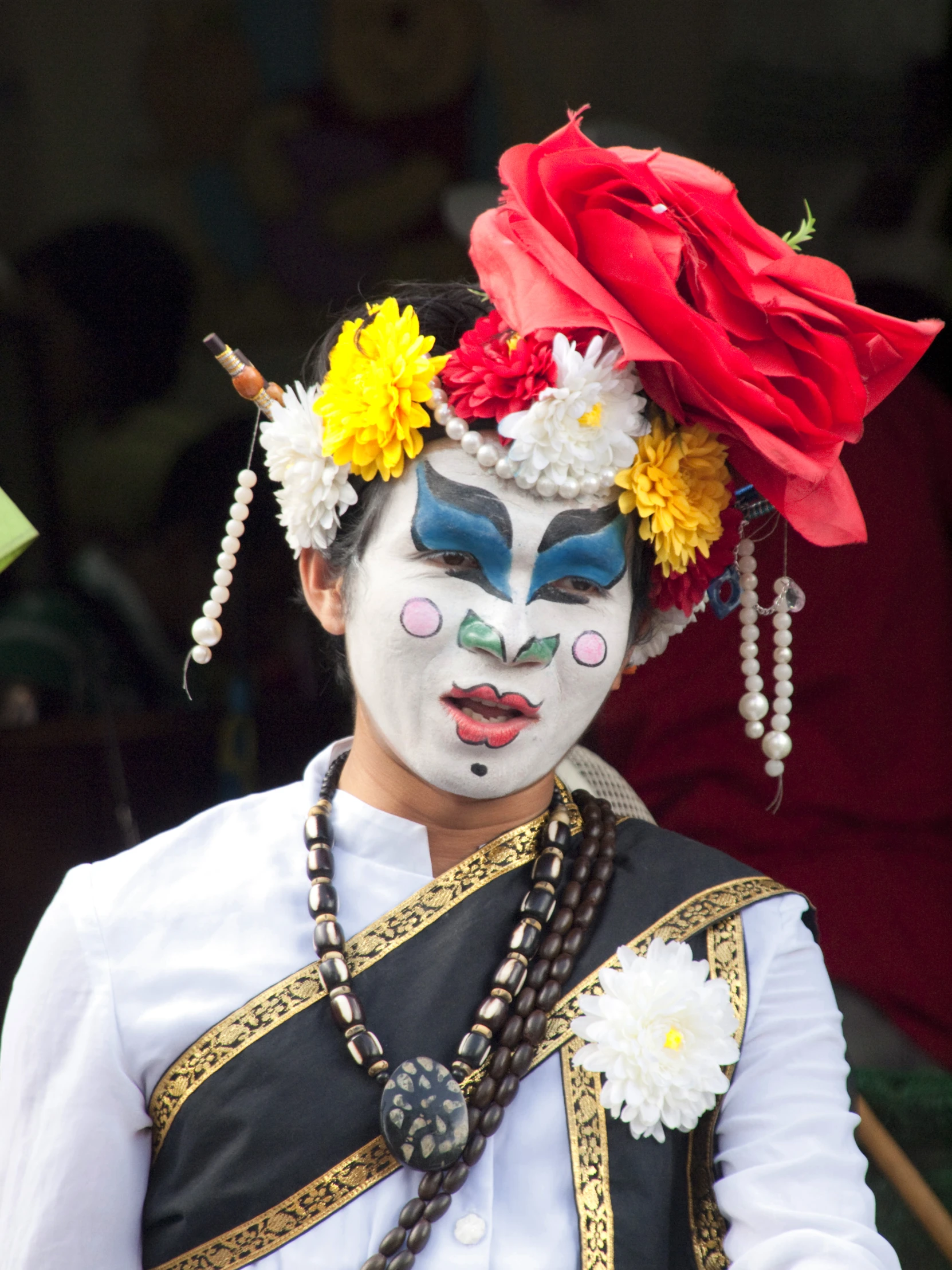 a woman in white with flowers on her head wearing white and red makeup