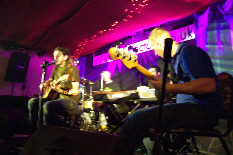 two young men playing guitar in front of microphones and recording