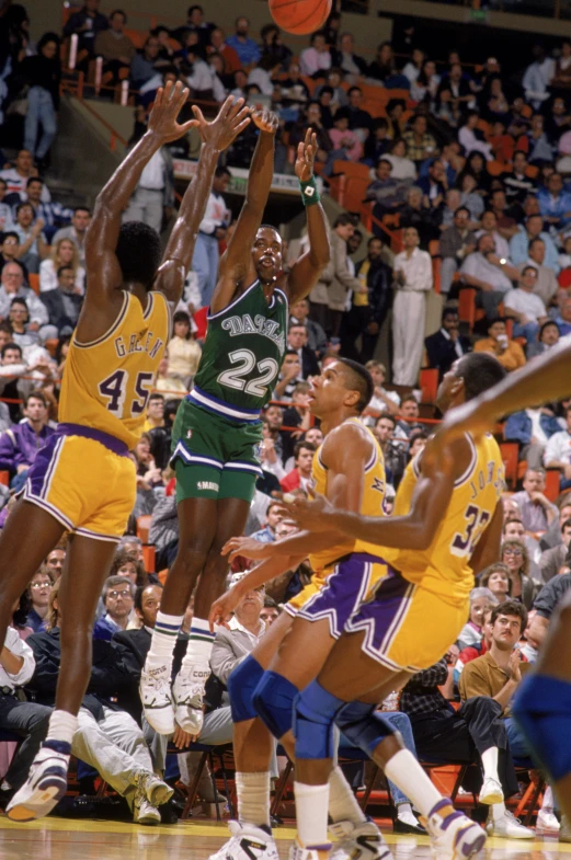 two basketball players trying to block the ball as others look on