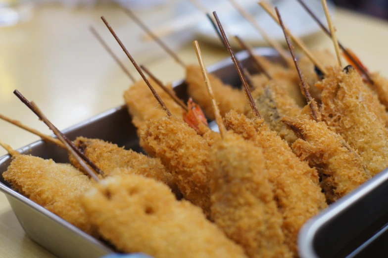 a tin container with food with several sticks sticking out of it