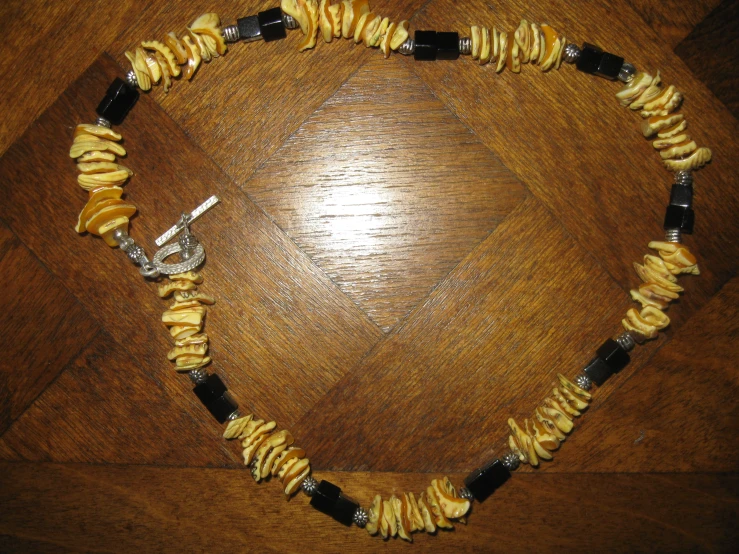 a necklace with black and yellow beads on a wooden surface