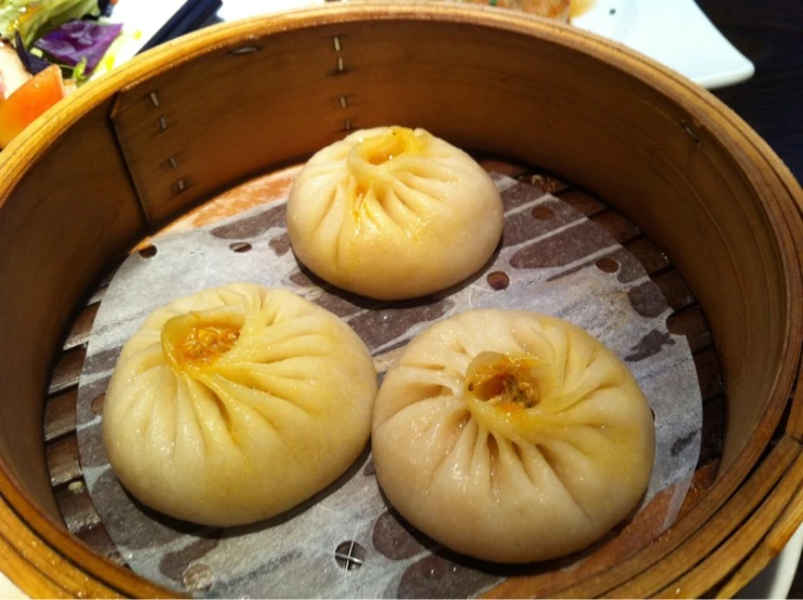 three dim steamed buns sitting on a table in front of a basket