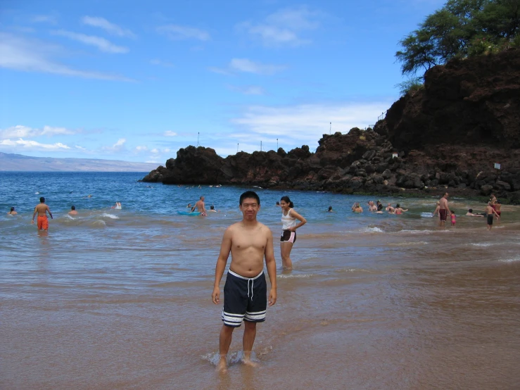 a young man standing on top of a sandy beach