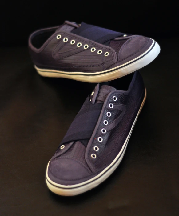 two purple shoes with white laces and one has two blue canvas shoes with a brown sole