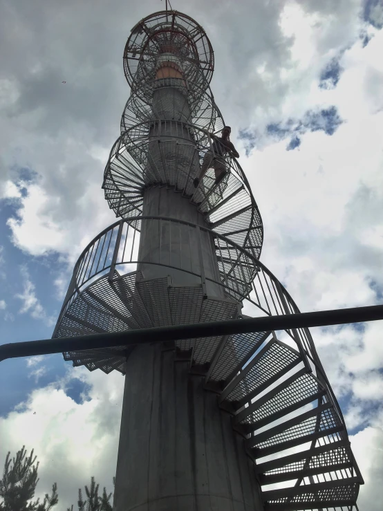 a tall clock tower with a spiral metal walkway running up the side