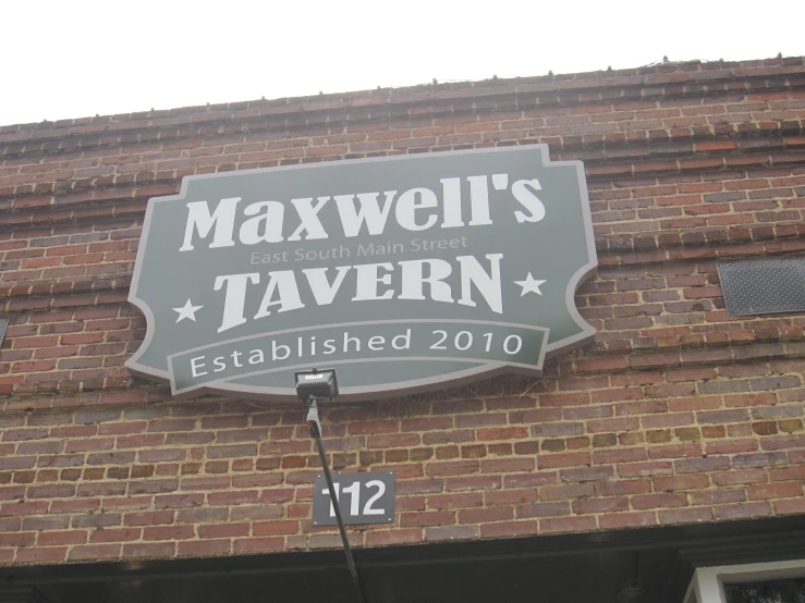 the restaurant sign for maxwell's tavern hanging on a brick building