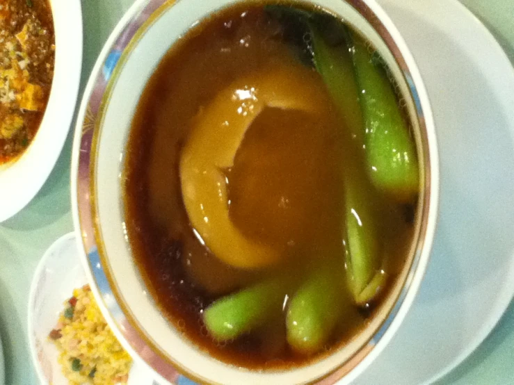 bowl of soup with a spoon and a green pepper on the rim