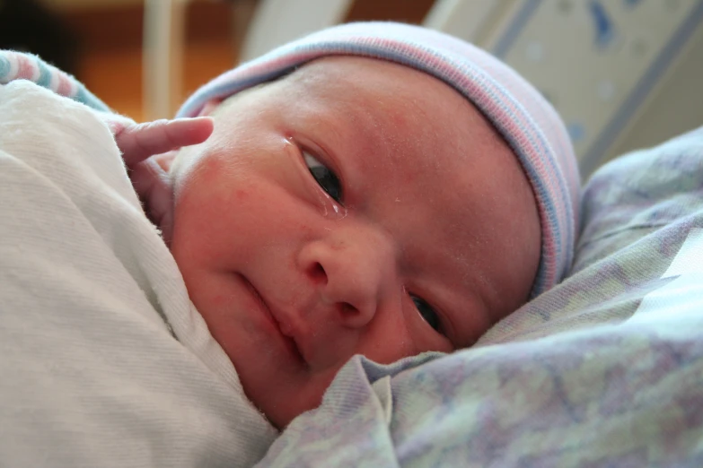 baby lying on a bed holding and looking at the camera