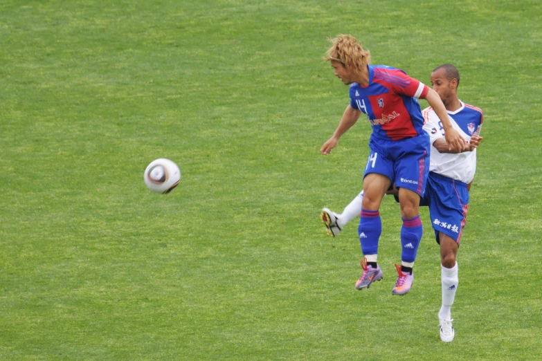 two men are in action on the grass playing soccer