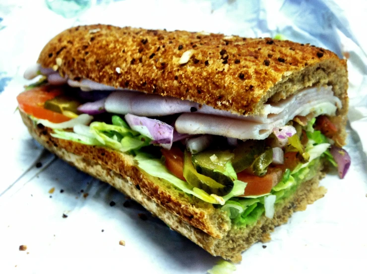 the sandwich has many different ingredients and has lettuce and tomato on it