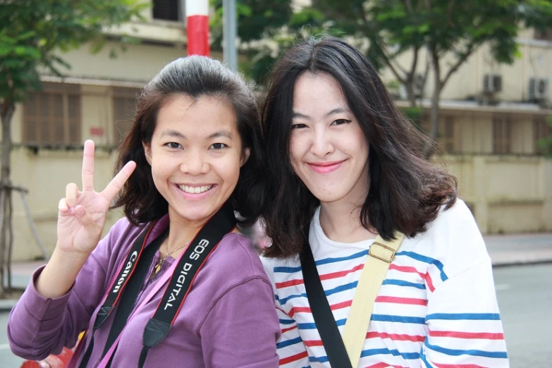 two women are making the peace sign outside