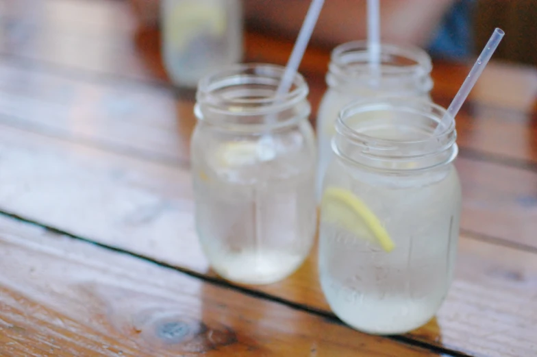 two mason jars with drinking straws sitting on a table