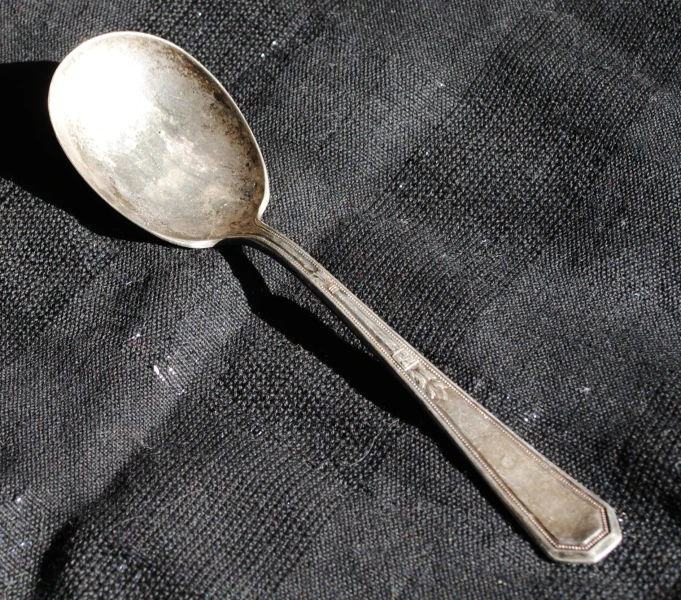 a spoon with an odd looking handle is placed on a gray piece of material