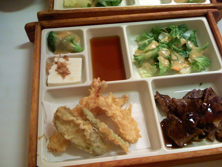 a chinese lunch is arranged in a bento box