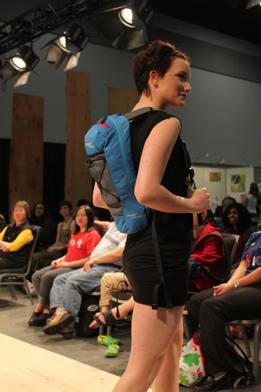 a woman with a backpack walking down the runway