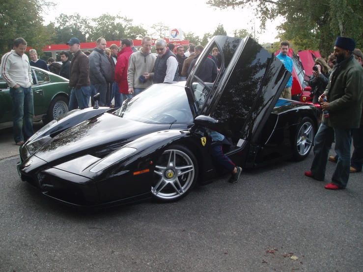 black sport car with people watching it on the street