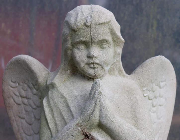 a white angel statue outside next to a wall