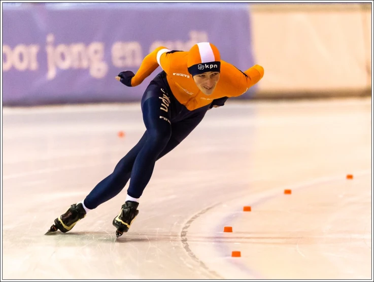 a man wearing an orange jacket is riding down a roller blade track