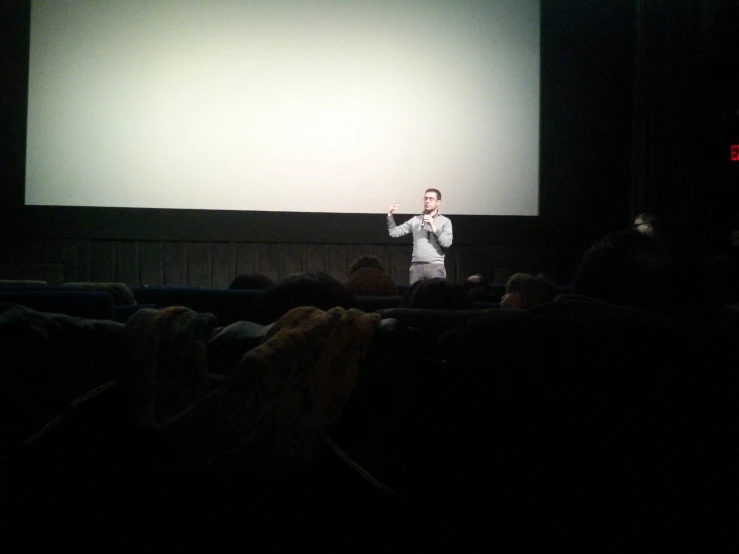 a man stands in front of a screen and gives a presentation