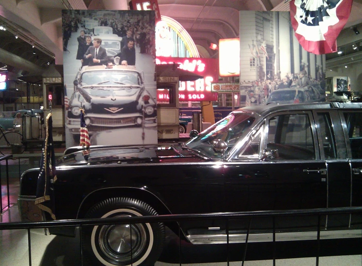 a black classic car is on display at a mall
