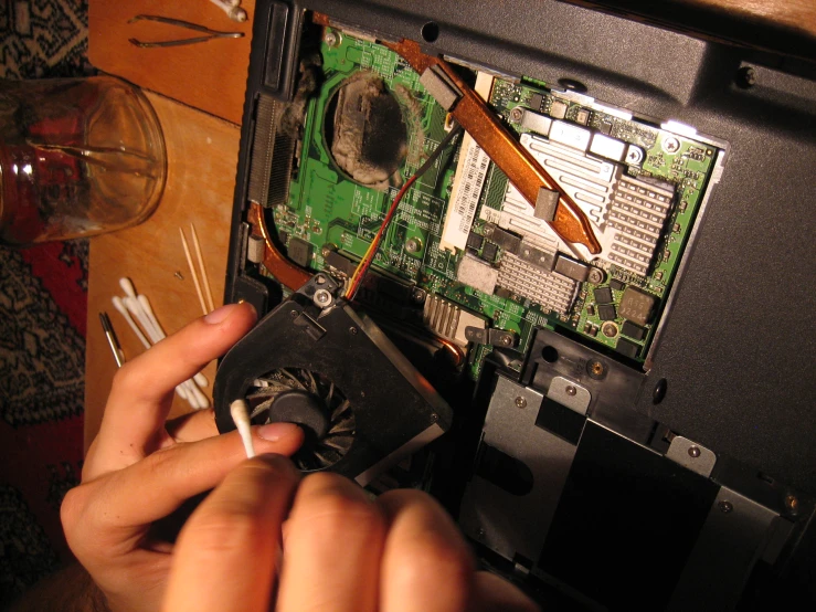 someone using a small screw to lift the motherboard up