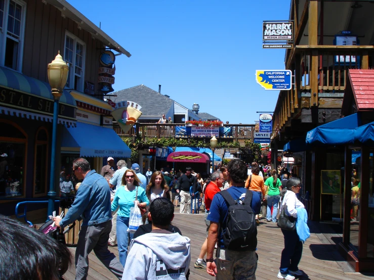 people walking and sitting on a boardwalk at a city area