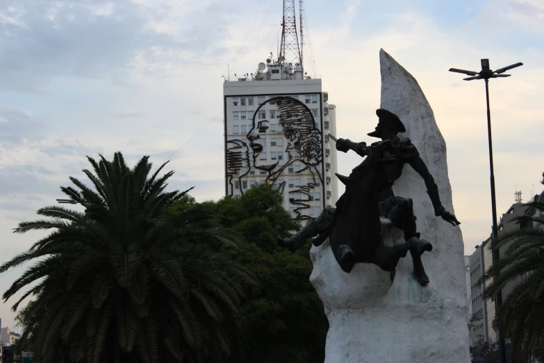 a statue of a man on a surfboard next to a tall building