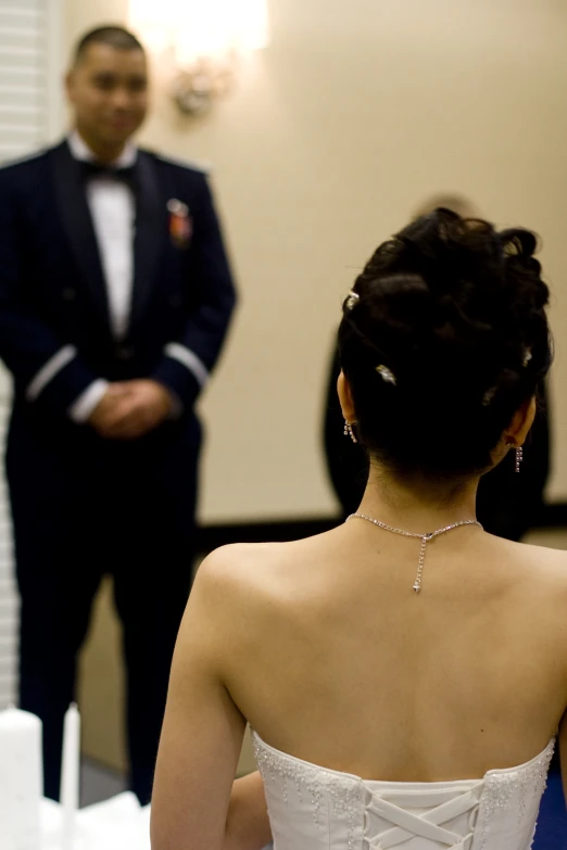 the back of a bride's dress as a man watches from behind