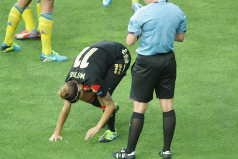 a soccer player is bent down on the ground while looking at his leg