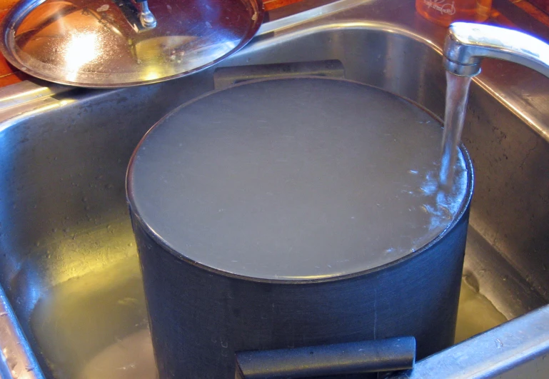 a pan sitting in a sink with a spout on top of it