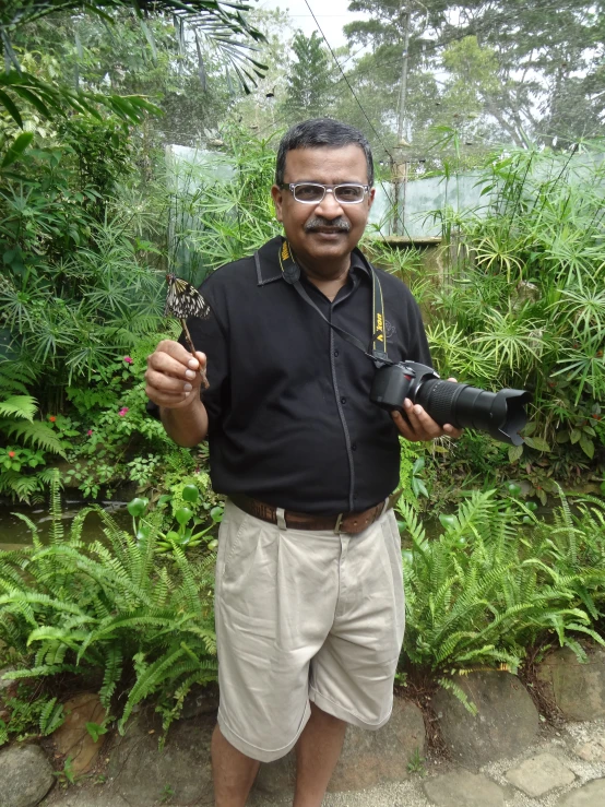 a man with a bird perched on his finger and holding a camera