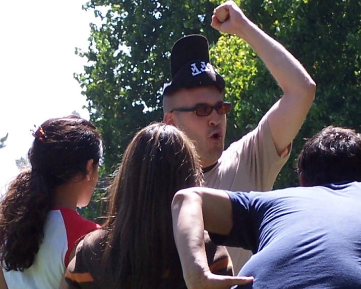 a man in a cap holds his arm in the air